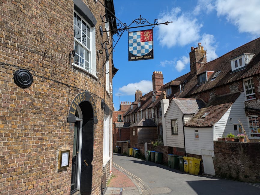 A street in Esher KT10 with a slight incline, lined with traditional and modern houses featuring brick and timber facades, some with bay windows and decorative elements. On the right side, a black and