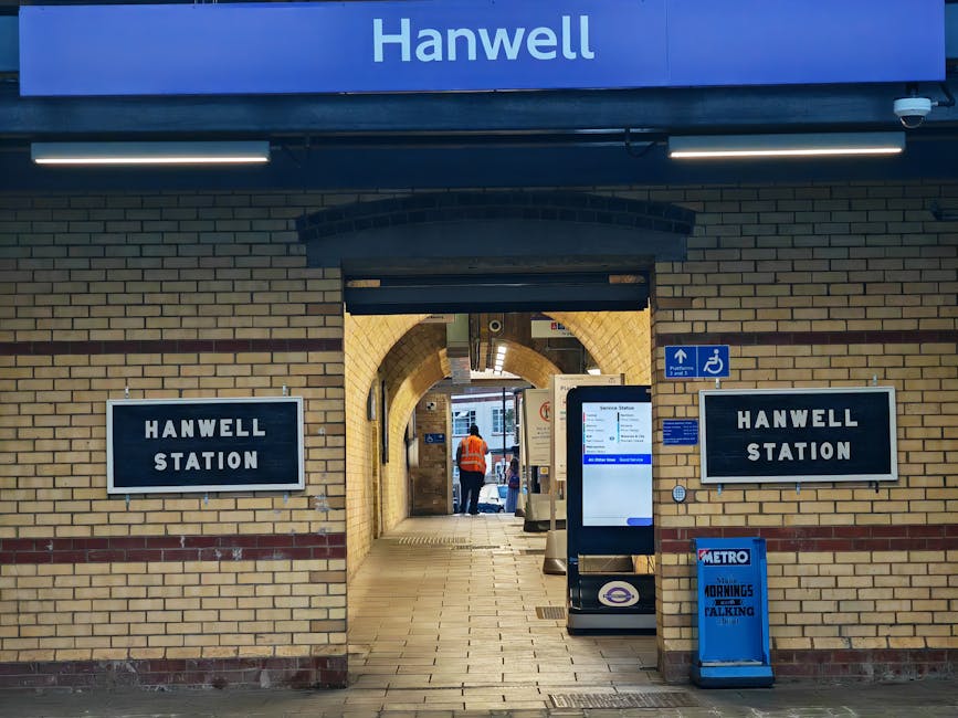 A view of Guildford Station in Surrey showing the platform with yellow tactile paving strips along the edge for passenger safety. The station building features a traditional brick facade with arched w